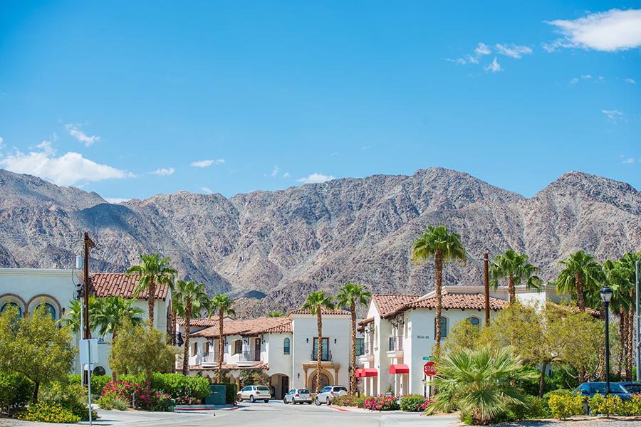 La Quinta, CA Insurance - Beautiful Buildings With Terra Cotta Tiled Roofs, White Walls, and Beautiful Landscaping, Surrounded by Palm Trees and Large Mountains